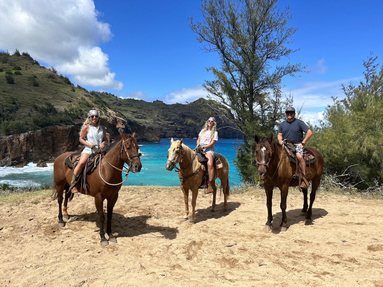 a group of people riding horseback on a beach